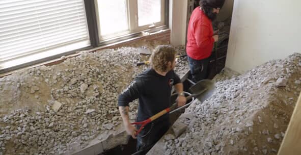 Workers shoveling gravel in a home