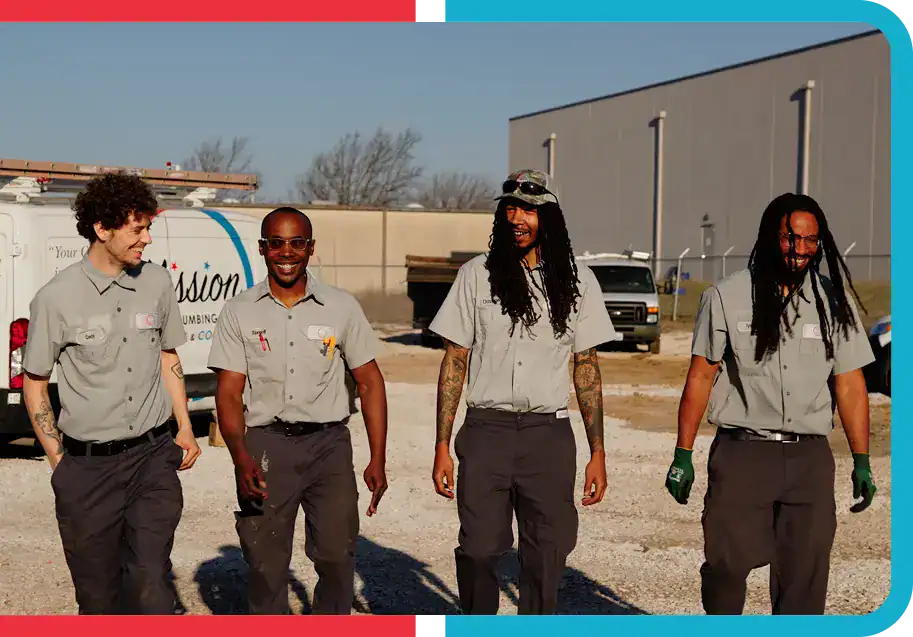 Four workers in matching gray uniforms walk together outside near a white van and industrial buildings on a sunny day.